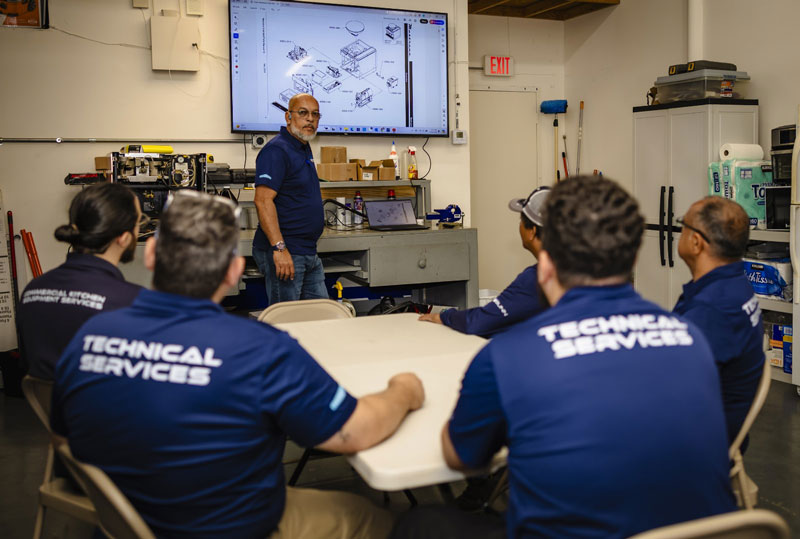 Santos Technical Services technicians in a training lab, enhancing skills in commercial kitchen maintenance and repair, specializing in coffee machines, refrigeration systems, and ice equipment. Expert team serving businesses in Boca Raton, Florida.