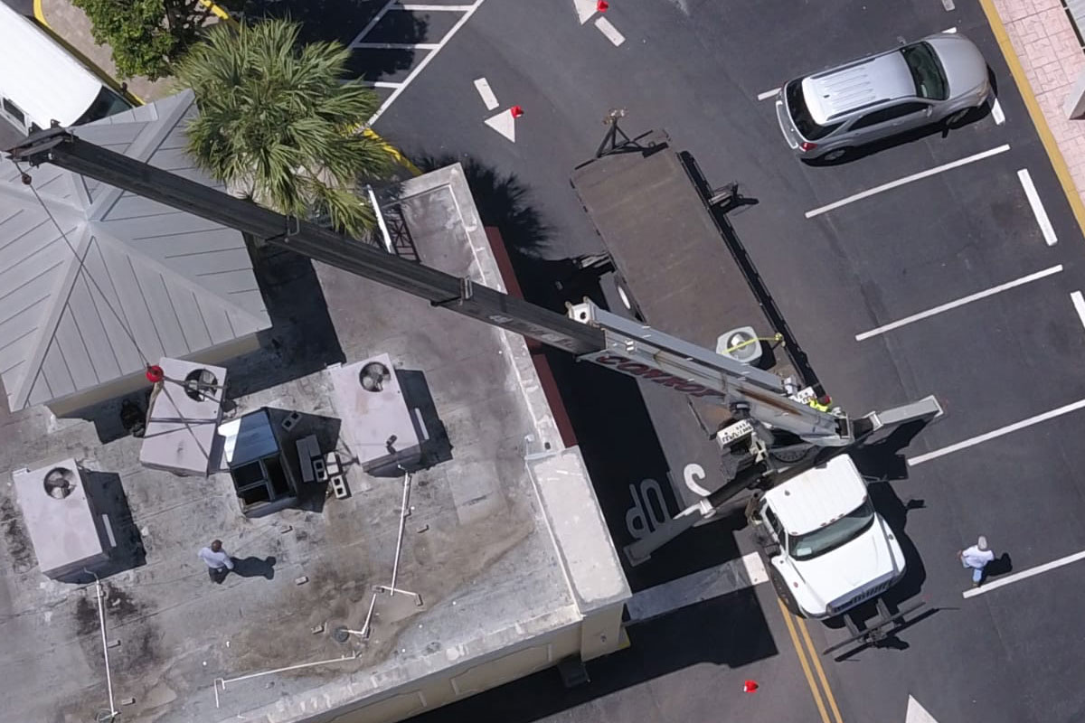 Air conditioning refrigeration system repair at a fast food establishment, featuring a crane lifting equipment to the rooftop. Santos Technical Services provides expert maintenance and repair for commercial HVAC systems, ensuring optimal performance for businesses in Boca Raton, Florida.